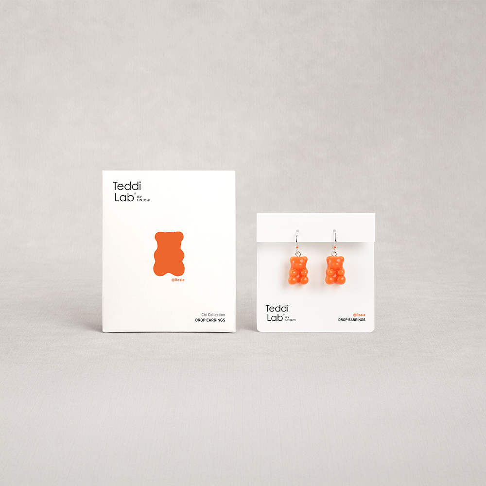 Gummy bear-shaped earrings on display with 'Teddi Lab' packaging on a gray background