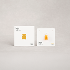 Two white boxes with yellow gummy bear-shaped pendants on a light gray background, branded 'Teddi Lab'.